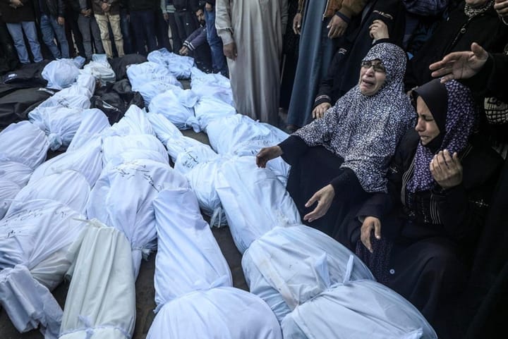 A mass funeral in Gaza with mourners and shrouded corpses.